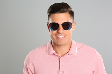 Photo of Handsome man wearing sunglasses on grey background