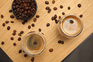 Photo of Tasty coffee and beans on wooden table, flat lay