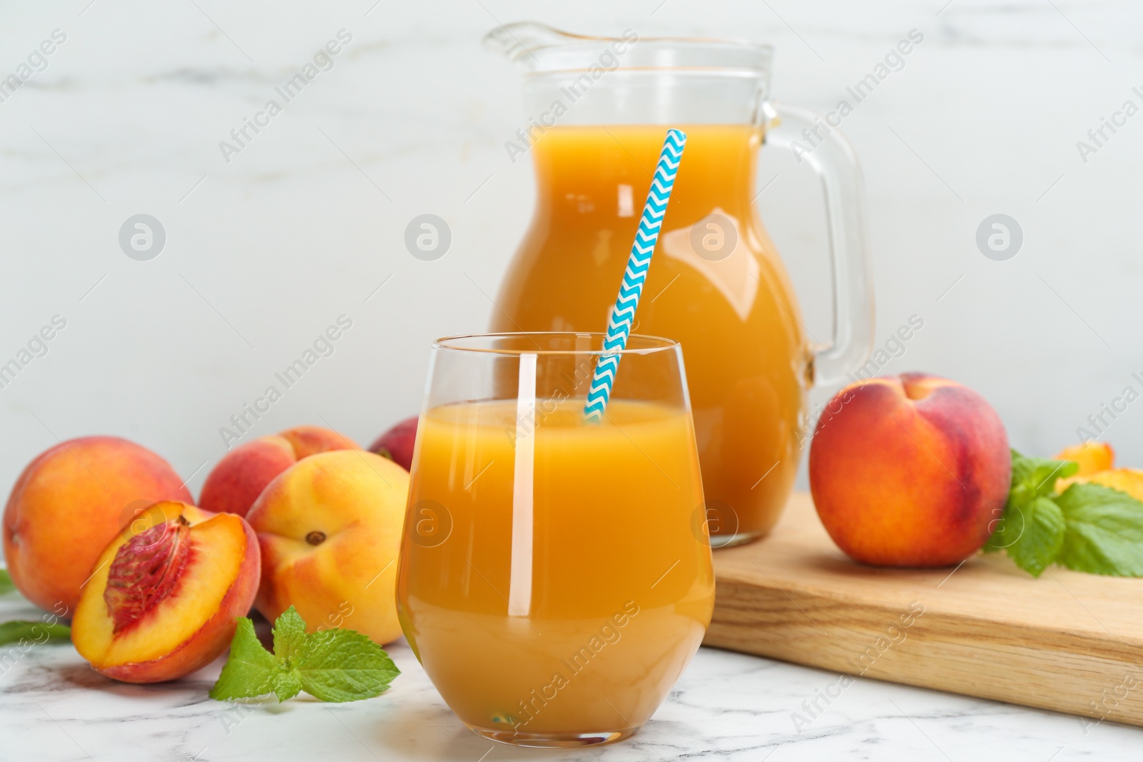 Photo of Natural peach juice and fresh fruits on white marble table