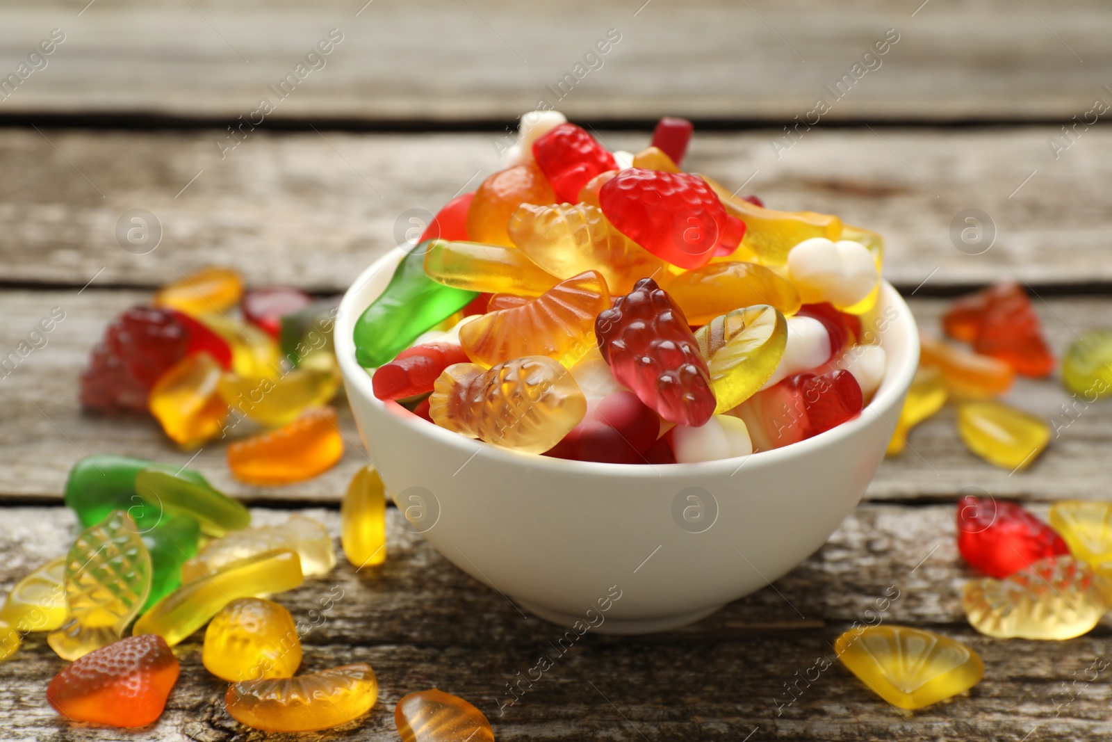 Photo of Delicious gummy fruit shaped candies on wooden table, closeup