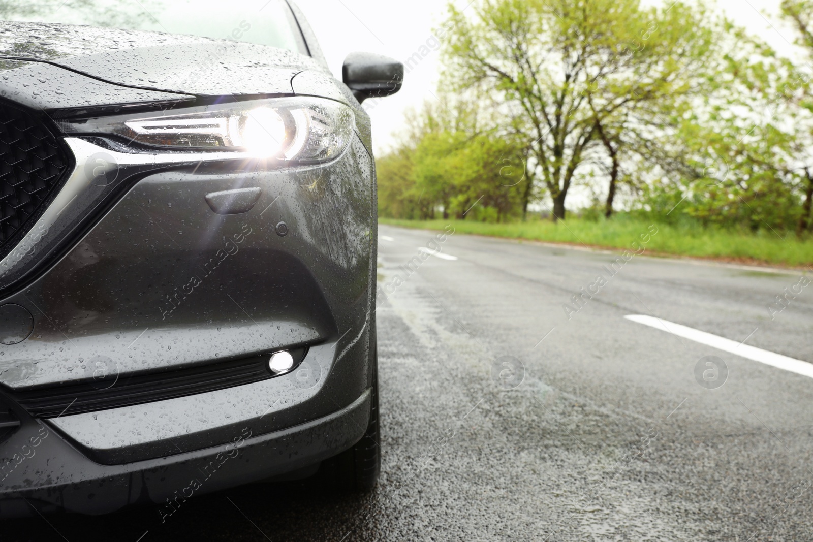 Photo of Modern car parked outdoors on rainy day