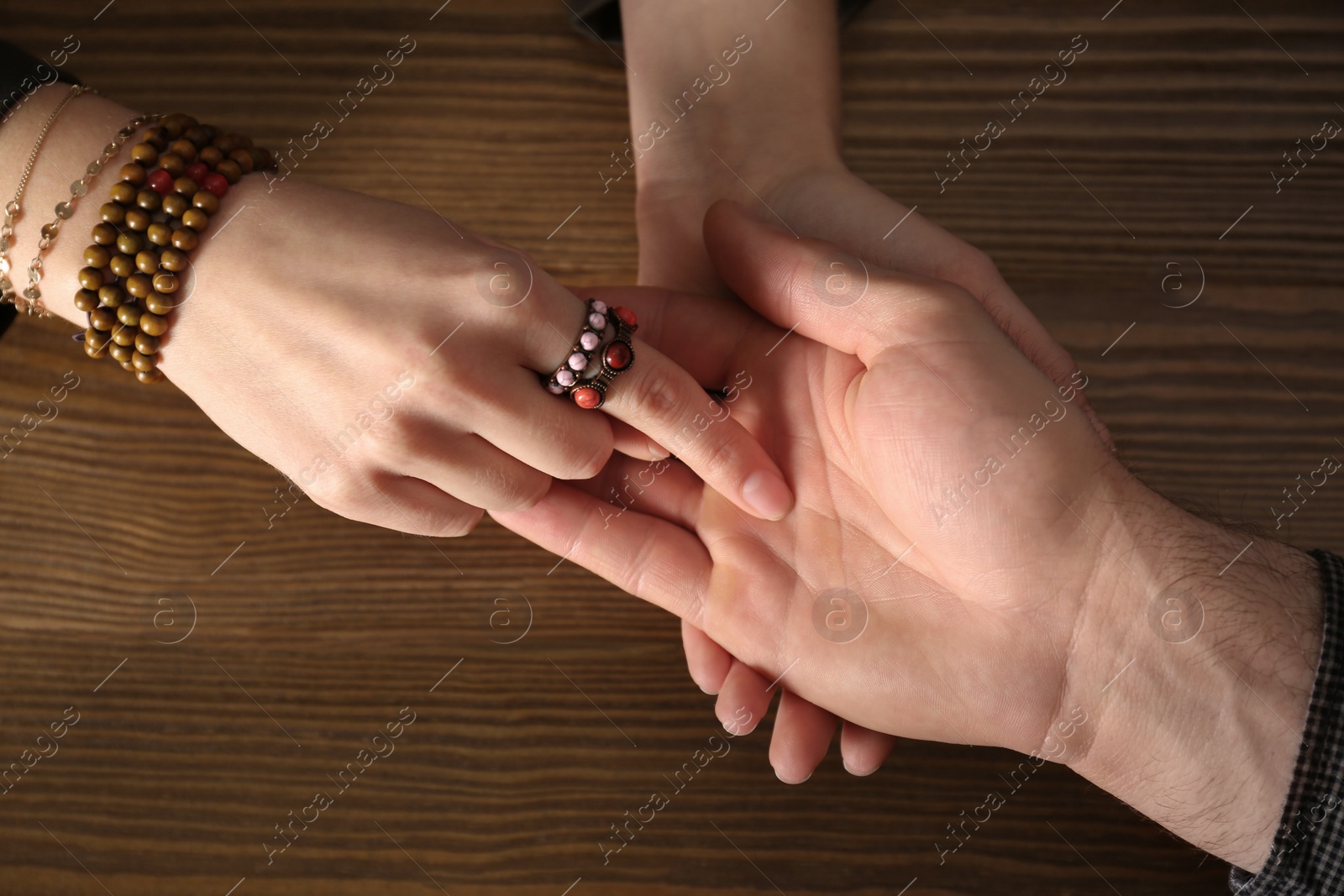 Photo of Chiromancer reading lines on man's palm at table, above view