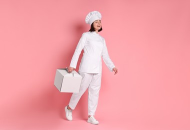 Photo of Happy confectioner with cake box on pink background