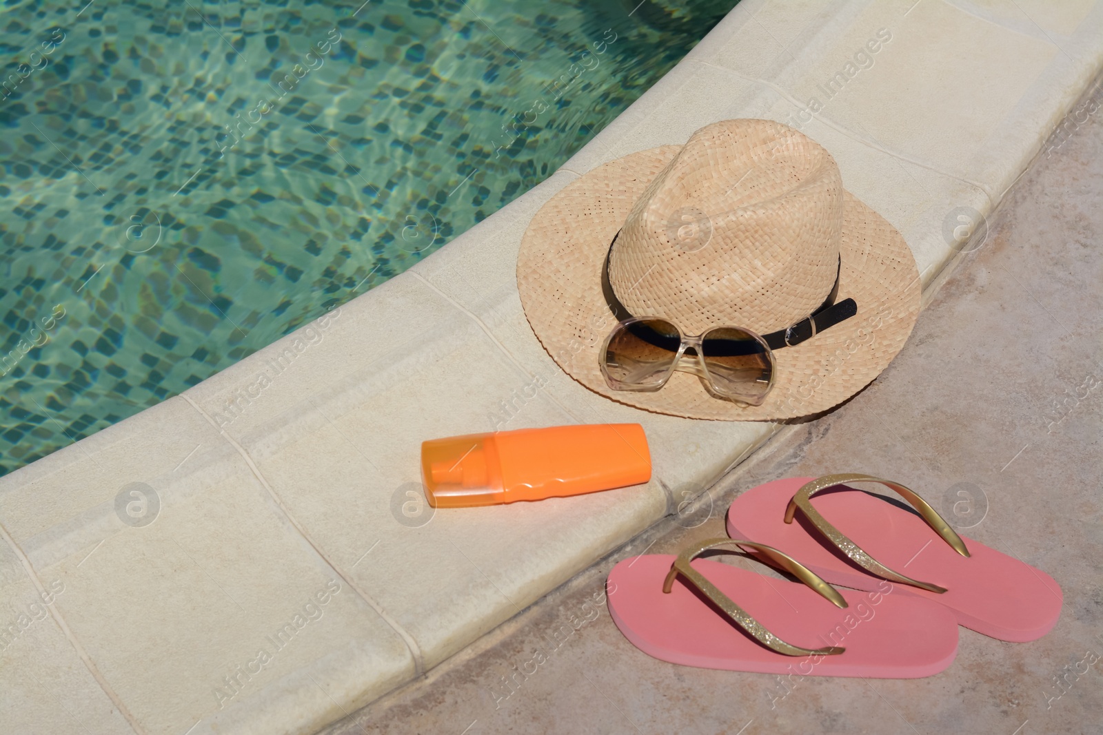 Photo of Different beach accessories near outdoor swimming pool on sunny day