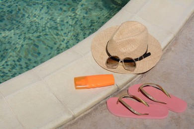 Photo of Different beach accessories near outdoor swimming pool on sunny day