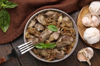 Photo of Delicious fried chicken liver with onion served on wooden table, flat lay