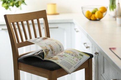 Photo of Open culinary magazine on chair in kitchen