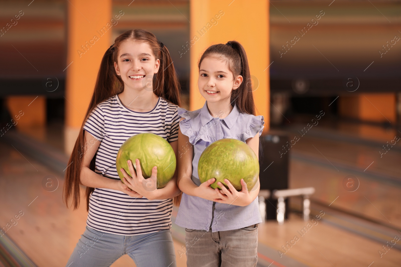 Photo of Happy girls with balls in bowling club