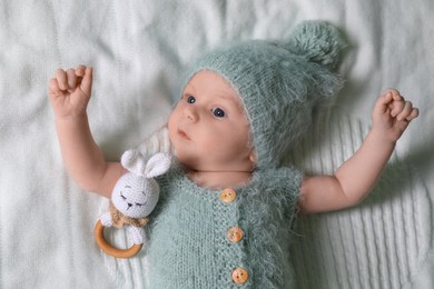 Photo of Cute newborn baby with teething toy on white blanket, top view