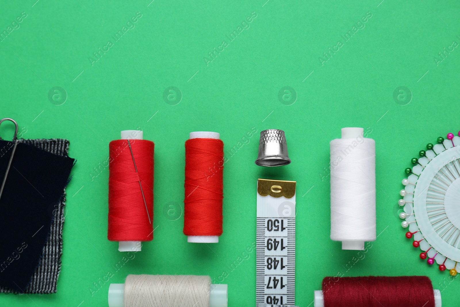 Photo of Flat lay composition with thimble and different sewing tools on green background. Space for text