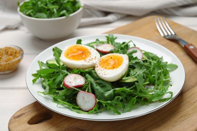 Photo of Delicious salad with boiled egg, vegetables and arugula on wooden board, closeup