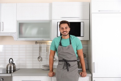 Photo of Young man near microwave oven in kitchen