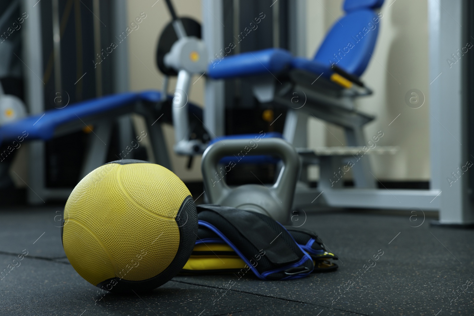 Photo of Yellow medicine ball, kettlebell and weighting agents on floor in gym, space for text