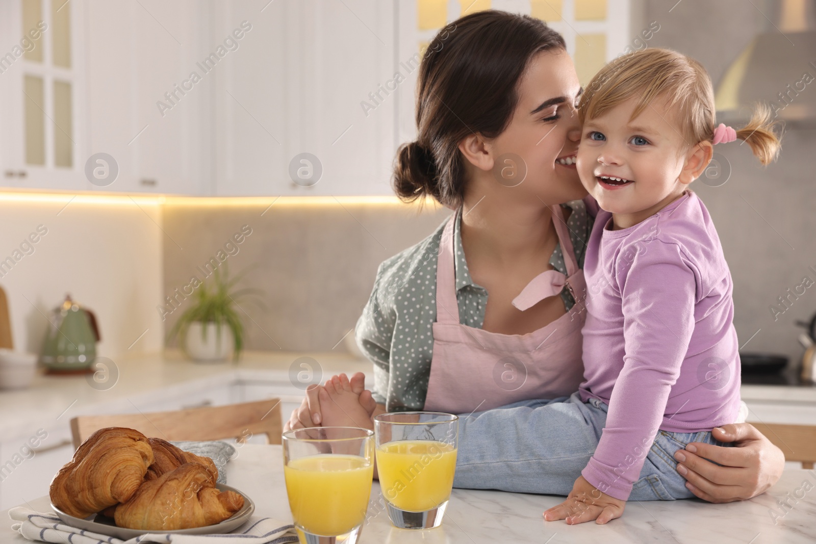 Photo of Mother and her little daughter having breakfast together in kitchen