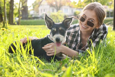 Photo of Teenage girl with her cute dog resting on green grass in park