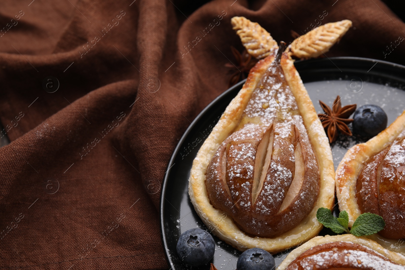Photo of Delicious pears baked in puff pastry with powdered sugar served on table, closeup. Space for text