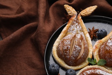 Delicious pears baked in puff pastry with powdered sugar served on table, closeup. Space for text
