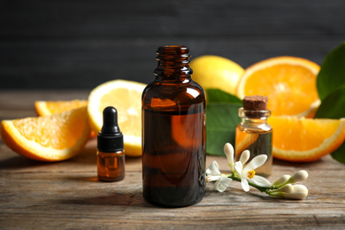 Photo of Bottles of citrus essential oil on wooden table