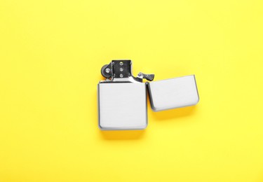 Photo of Gray metallic cigarette lighter on yellow background, top view