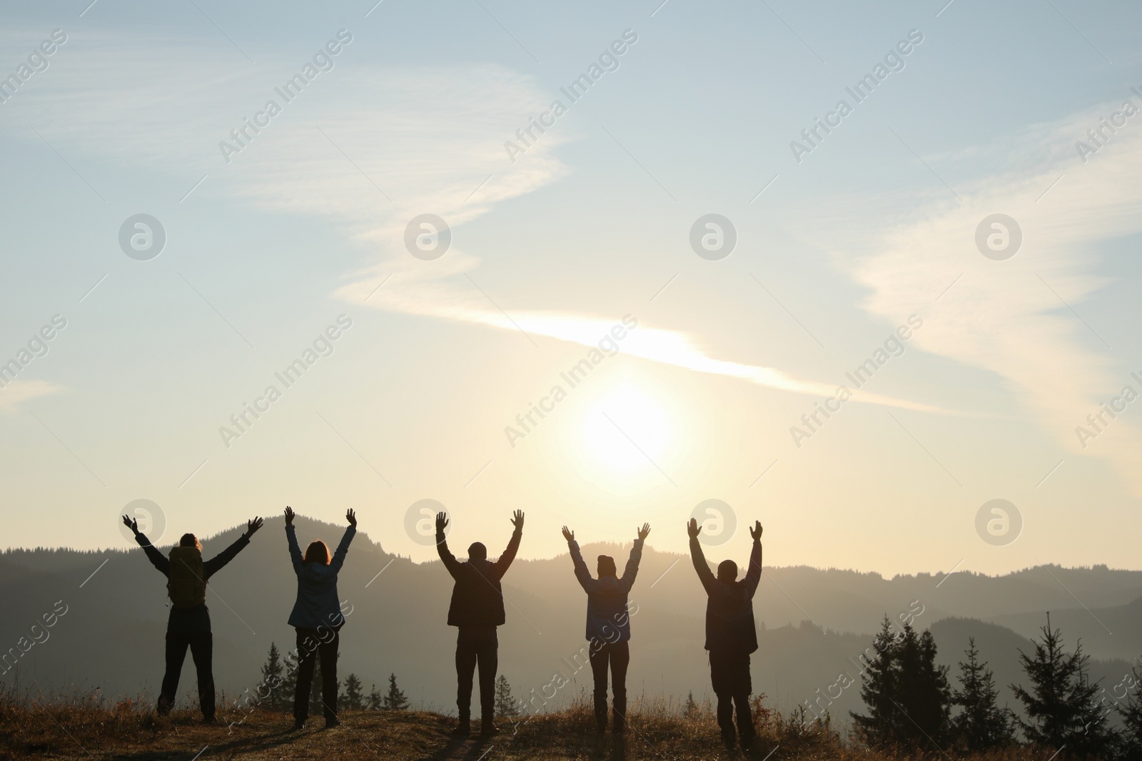 Photo of Group of people enjoying sunrise in mountains, back view. Space for text