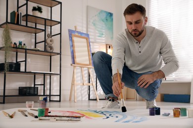 Young man painting on canvas with brush in artist studio