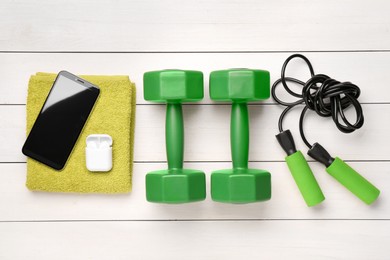 Flat lay composition with dumbbells on white wooden table