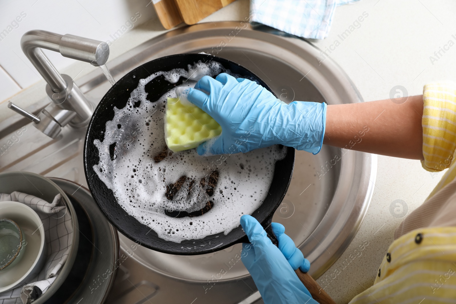 Photo of Woman washing dirty frying pan in sink, above view