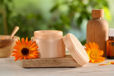 Photo of Different cosmetic products and beautiful calendula flowers on white wooden table outdoors