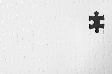 Blank white puzzle with missing piece on black background, top view. Space for text