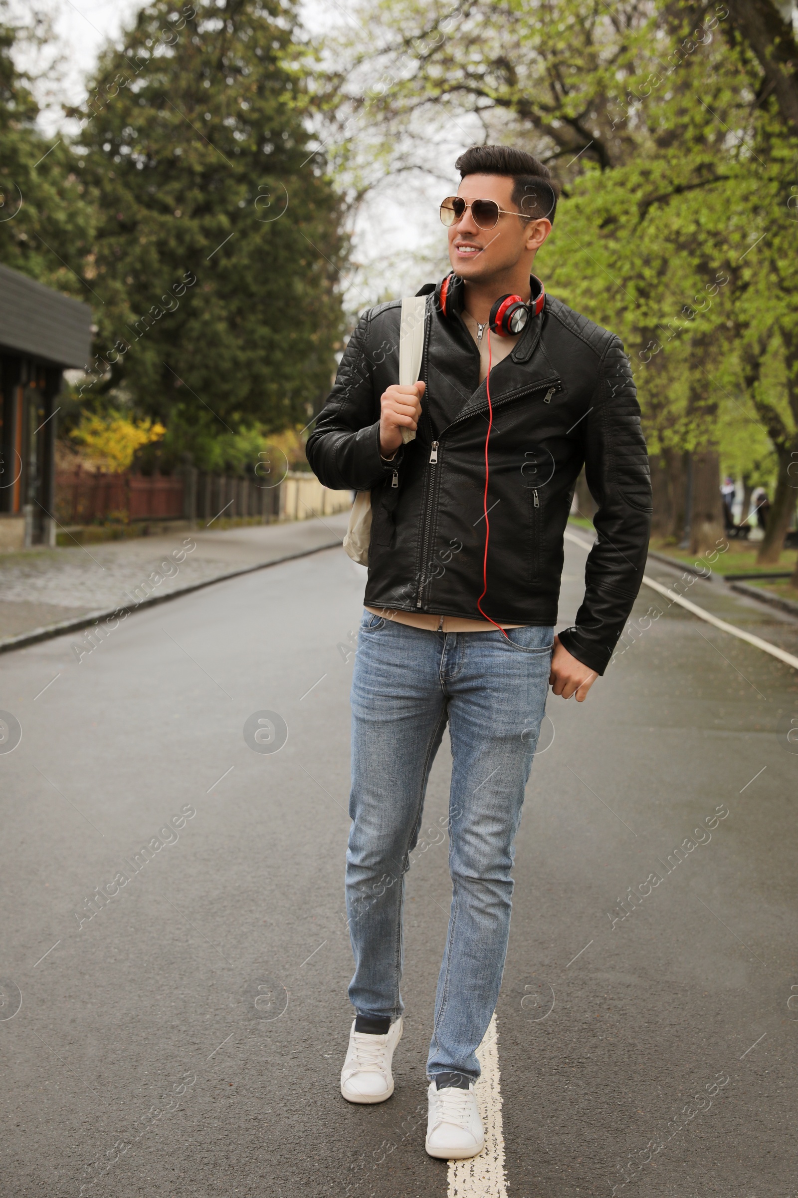 Photo of Tourist with headphones and sunglasses on city street