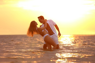 Photo of Happy young couple spending time together on sea beach at sunset