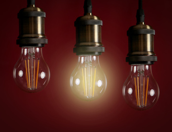 Image of Idea concept. Glowing light bulb among others on red background 
