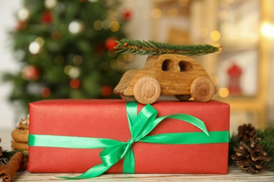 Photo of Beautiful Christmas gift box and toy car on white table, closeup