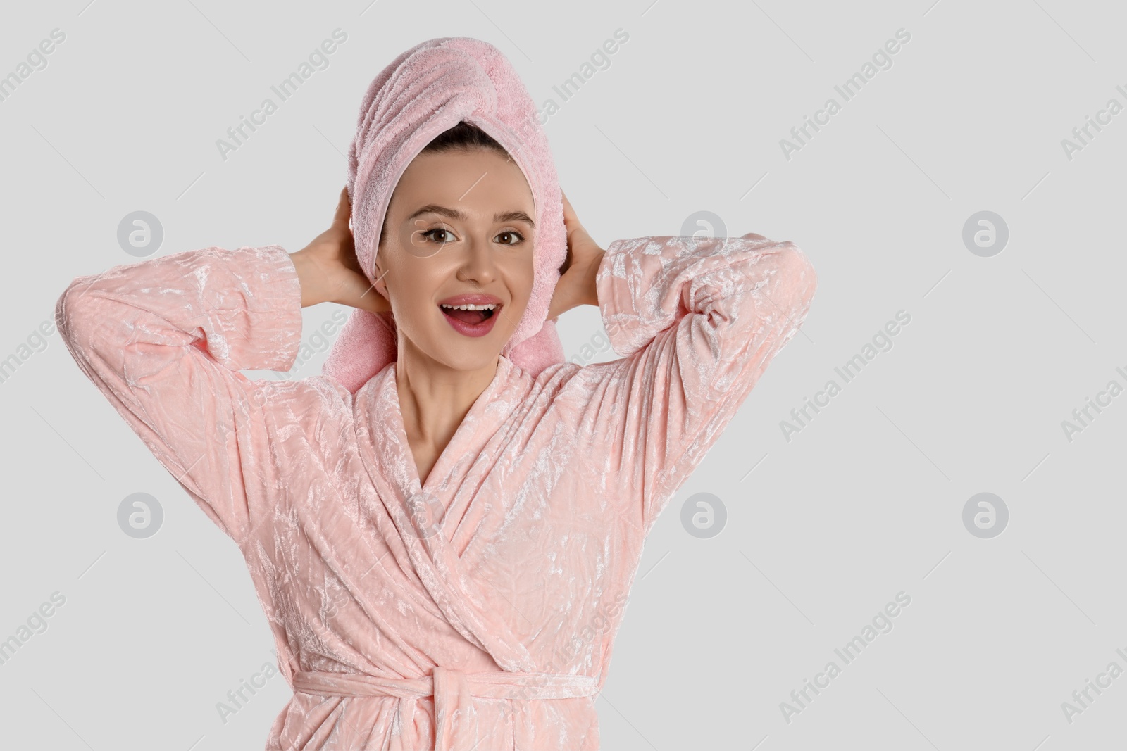 Photo of Beautiful young woman in bathrobe on light background