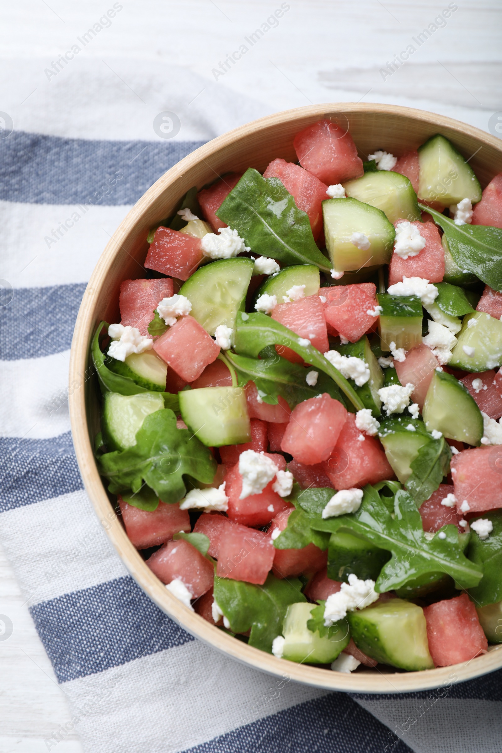 Photo of Delicious salad with watermelon, cucumber, arugula and feta cheese on white wooden table, flat lay