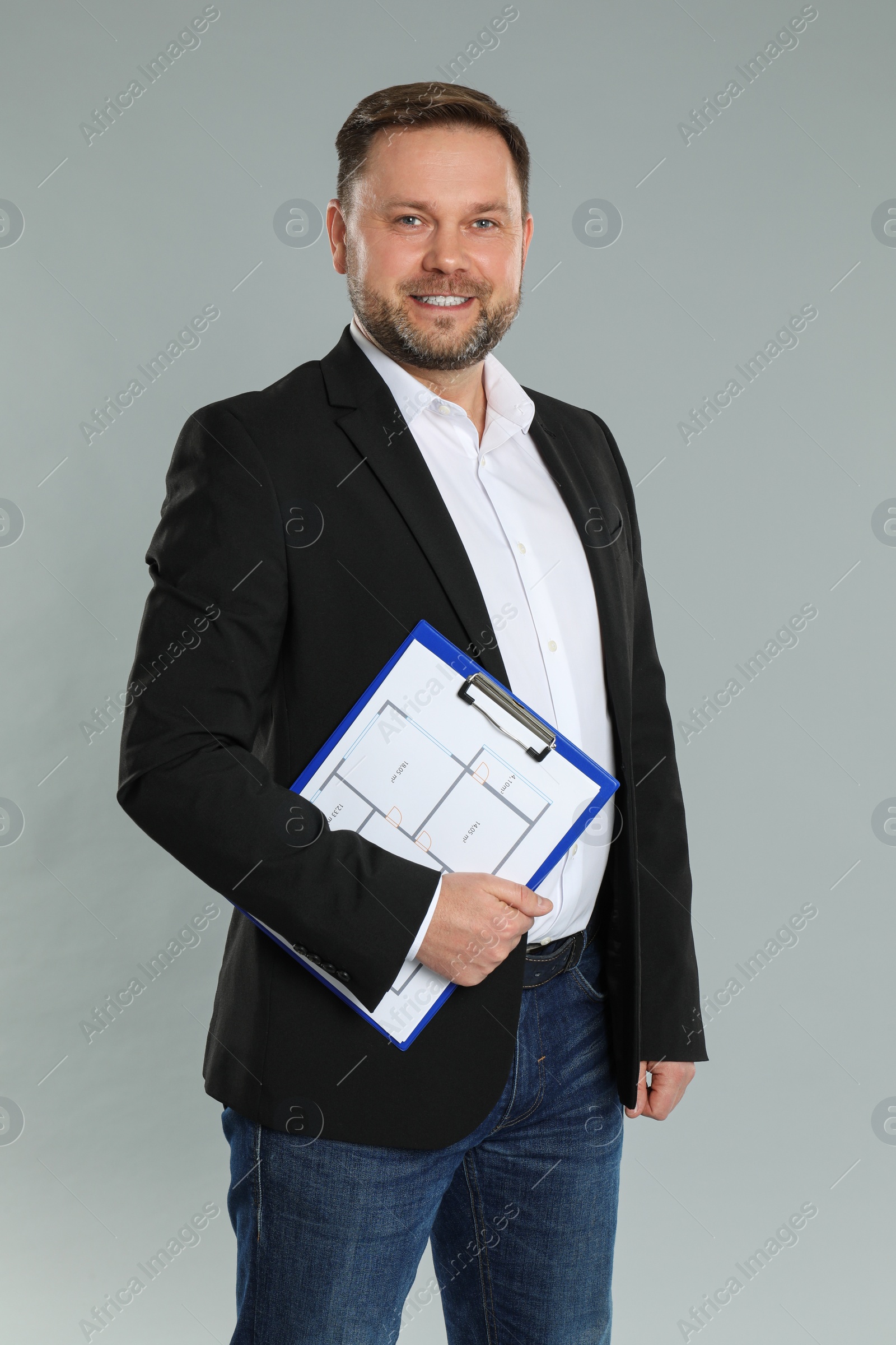 Photo of Male real estate agent with clipboard on grey background