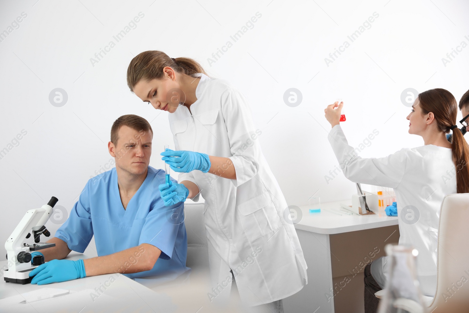 Photo of Scientist showing test tube to colleague with microscope in laboratory. Medical research