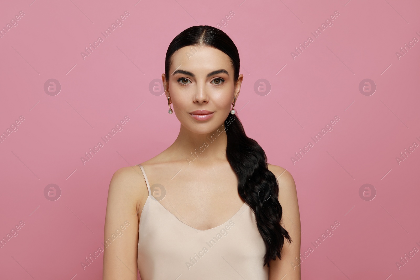 Photo of Young woman wearing elegant pearl earrings on pink background
