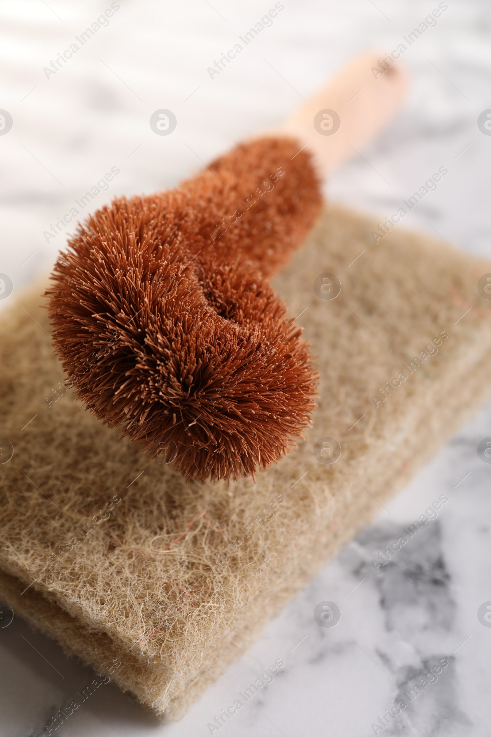 Photo of One cleaning brush and sponges on white marble table, closeup