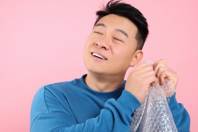 Photo of Asian man with bubble wrap on pink background