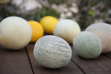 Tasty ripe melons on wooden table outdoors