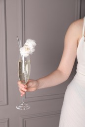 Woman holding glass of cotton candy cocktail near grey wall, closeup