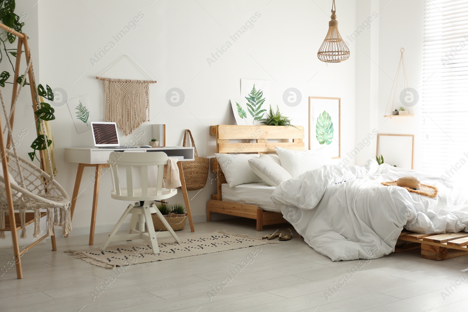 Photo of Stylish room interior with workplace, hanging chair and bed