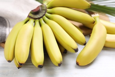 Photo of Tasty ripe baby bananas on white wooden table, closeup