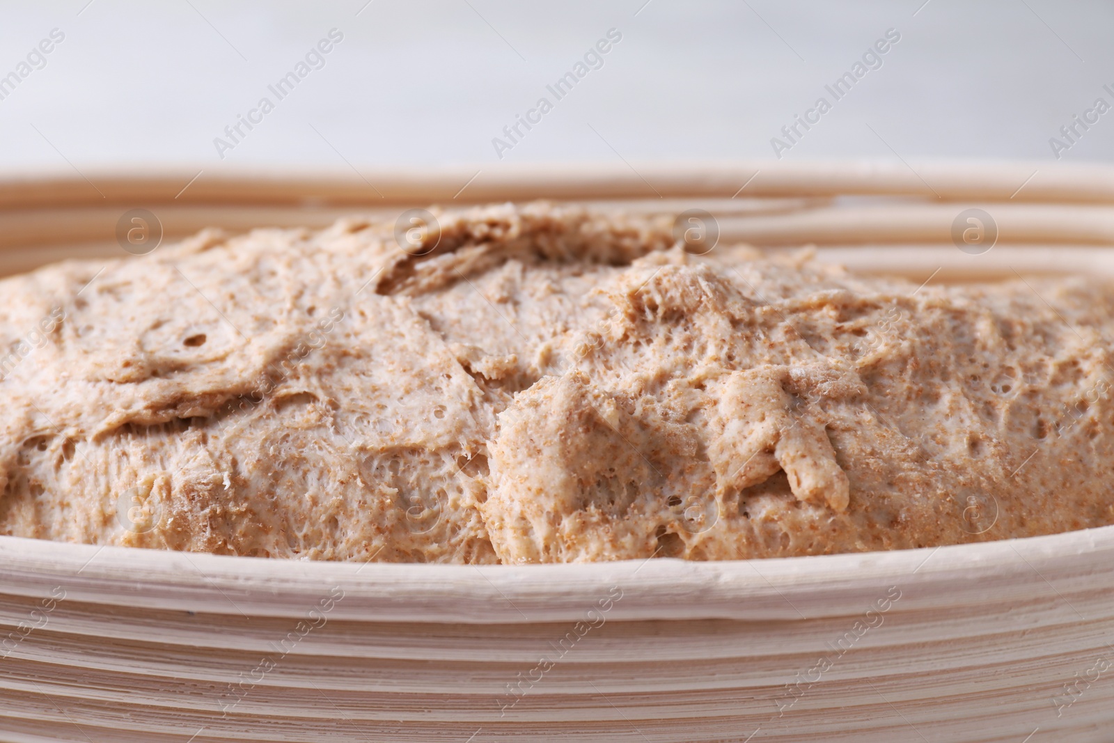 Photo of Fresh sourdough in proofing basket on table, closeup