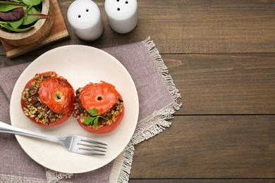 Photo of Delicious stuffed tomatoes with minced beef, bulgur and mushrooms served on wooden table, flat lay. Space for text