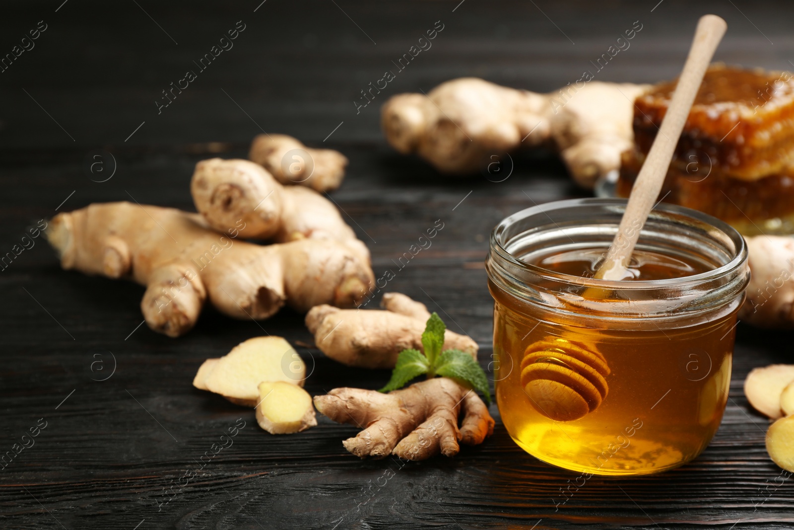 Photo of Honey and ginger on black wooden table. Natural cold remedies