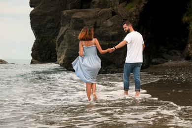 Photo of Young couple walking on beach near sea