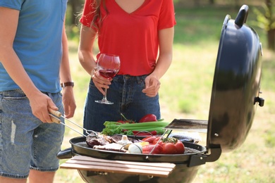 Young couple having barbecue with modern grill outdoors