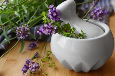 Photo of Mortar with fresh lavender flowers, green twigs and pestle on wooden table
